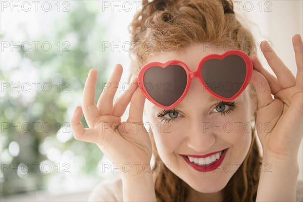 Caucasian woman peeking from heart-shape sunglasses