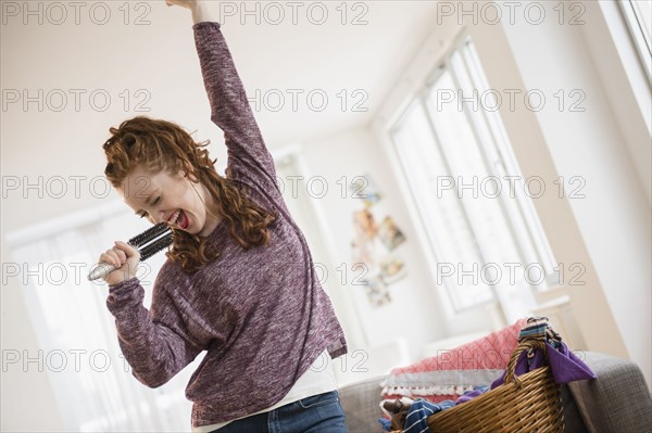 Caucasian woman singing with hairbrush microphone