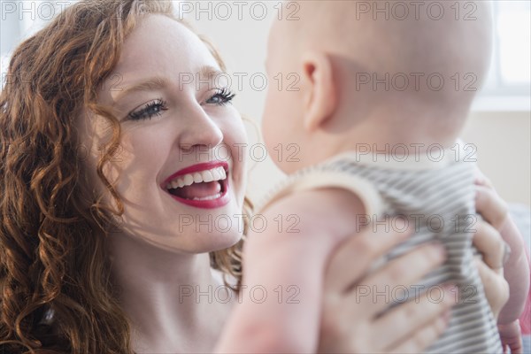Caucasian woman holding baby son face to face