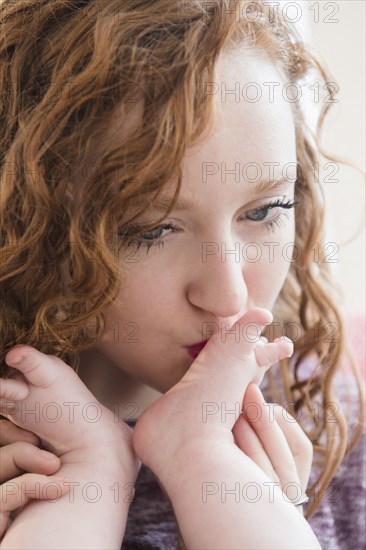 Caucasian woman kissing foot of baby son