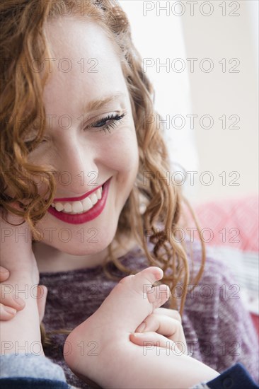 Caucasian woman holding foot of baby son