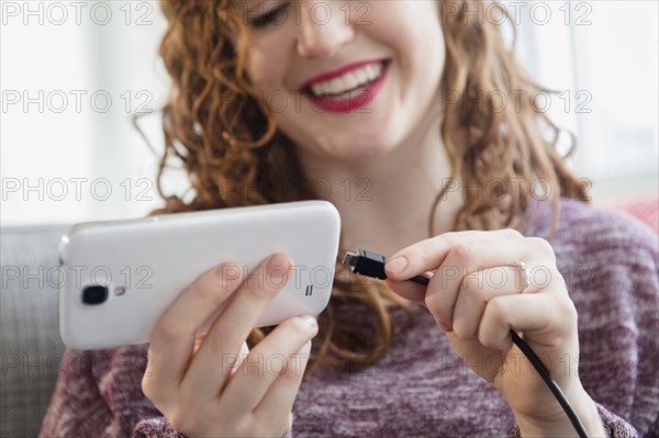 Caucasian woman connecting cord to cell phone