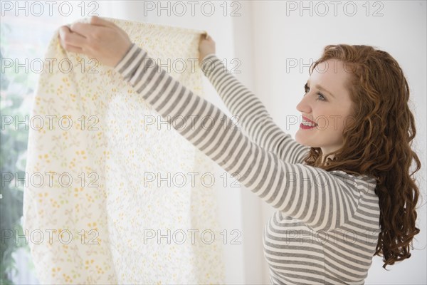 Caucasian woman holding curtain at window