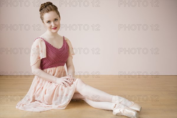 Caucasian ballerina sitting on floor