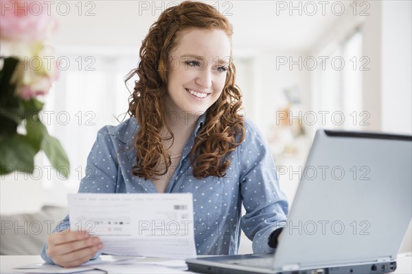 Caucasian woman paying bills using laptop