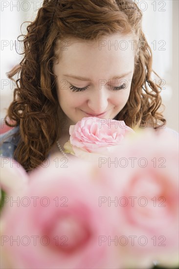 Caucasian woman smelling pink rose