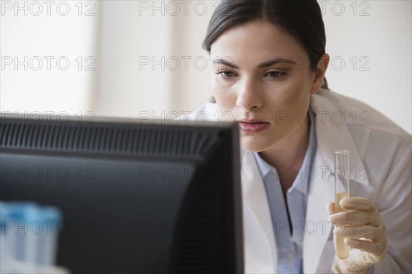 Caucasian scientist holding vial using computer