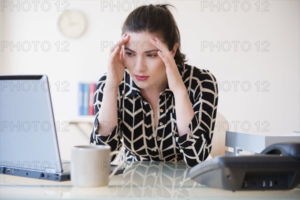Caucasian businesswoman with headache using laptop