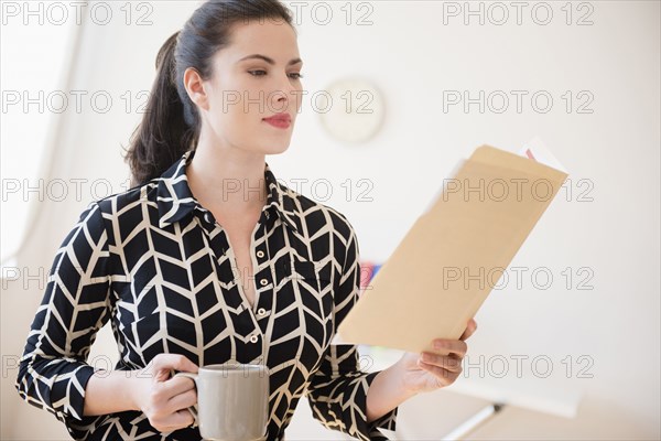 Caucasian businesswoman reading paperwork in file folder