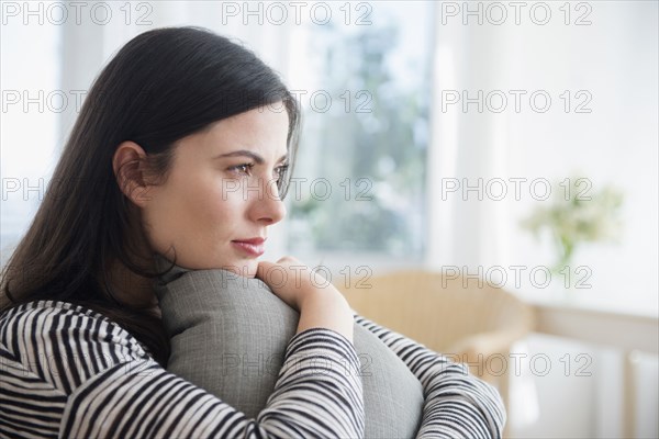 Pensive Caucasian woman clutching pillow