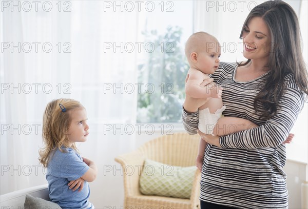 Caucasian daughter jealous of mother holding baby sister