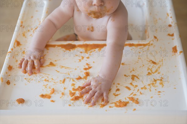 Caucasian baby girl self-feeding mashed sweet potato