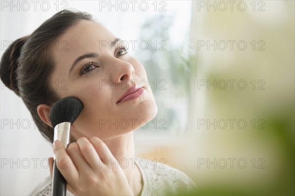 Caucasian woman applying blush