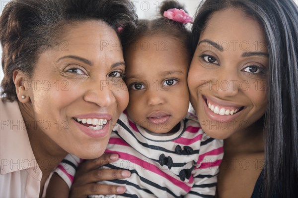 Black multi-generation family posing cheek to cheek