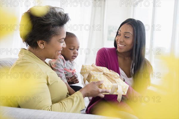 Black multi-generation family exchanging gift