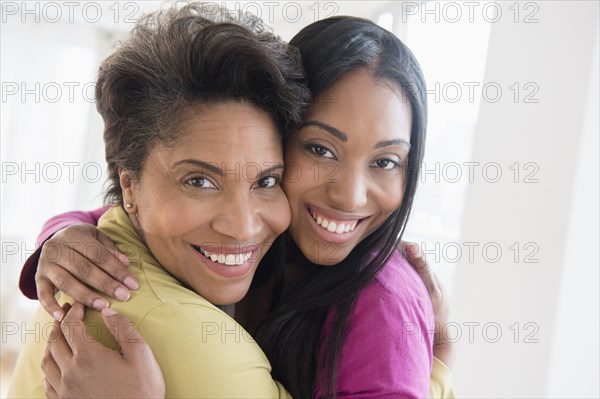 Black women hugging cheek to cheek