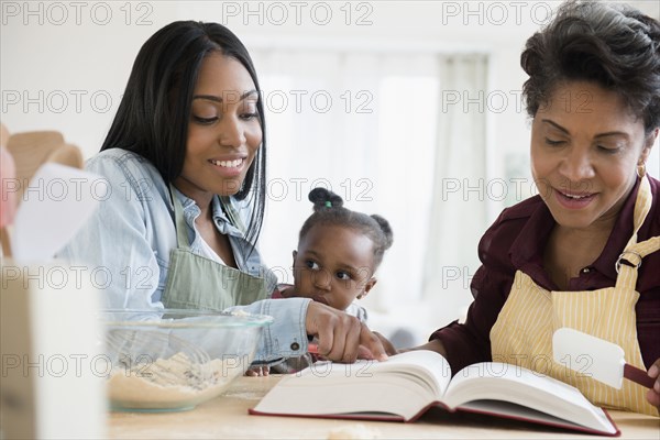 Black multi-generation family reading recipe in cookbook
