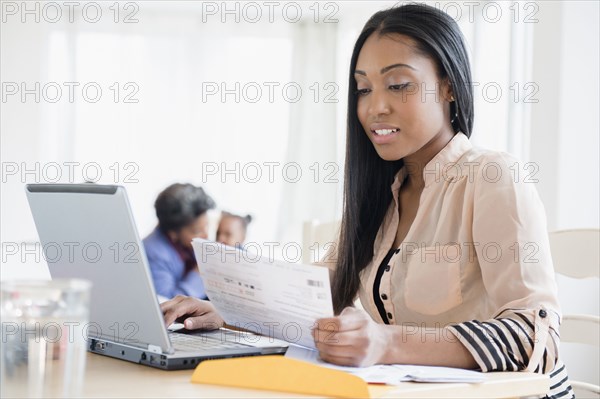 Black woman paying bills using laptop