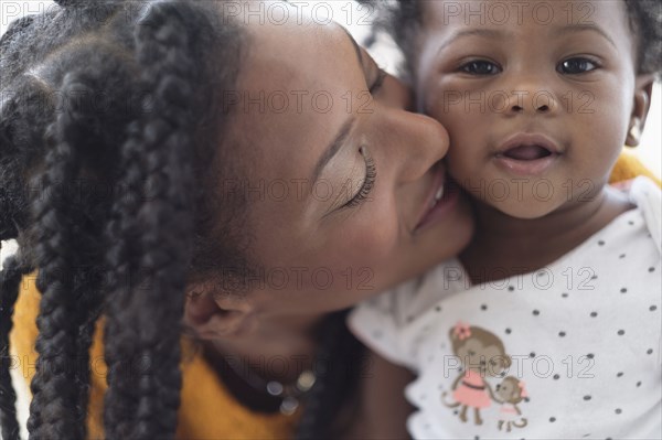 Smiling Black woman cheek to cheek with baby daughter