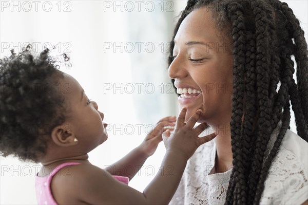 Black woman playing with baby daughter