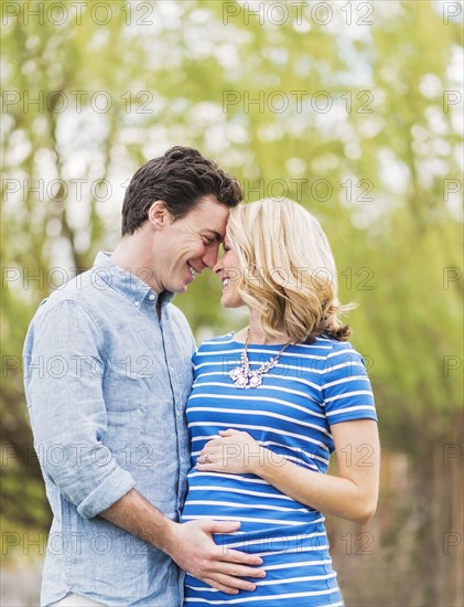 Smiling Caucasian man and expectant mother rubbing noses