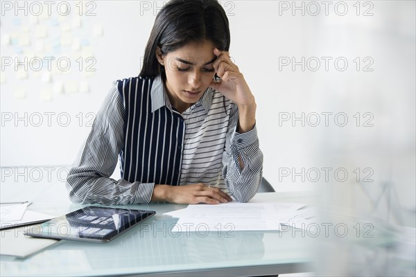 Indian businesswoman reading paperwork in office