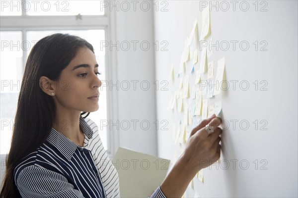 Indian businesswoman reading adhesive notes in office