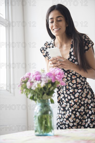 Indian woman photographing flowers with cell phone