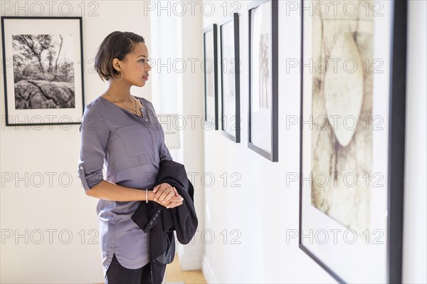 Black woman admiring paintings in art gallery