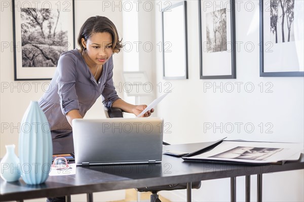 Black businesswoman using laptop in art gallery office