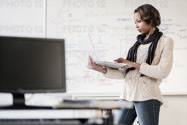 Black businesswoman using laptop near whiteboard
