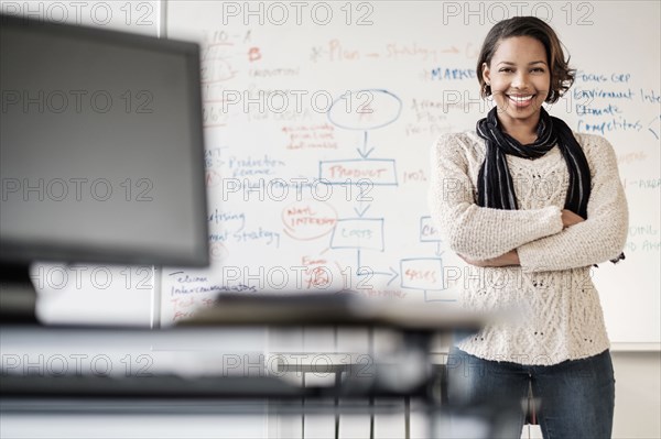 Black businesswoman posing in office near whiteboard