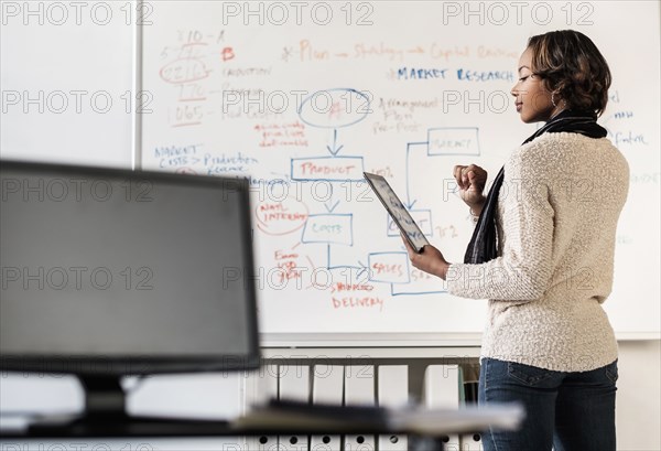 Black businesswoman using digital tablet in office near whiteboard