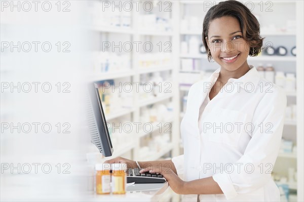 Smiling Black pharmacist using computer