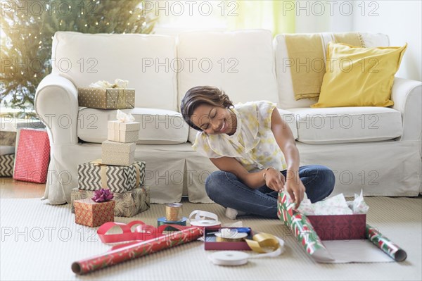 Black woman sitting on floor wrapping gifts