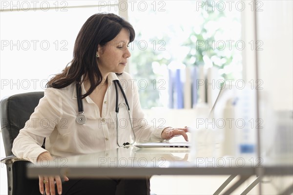 Hispanic doctor using laptop in office