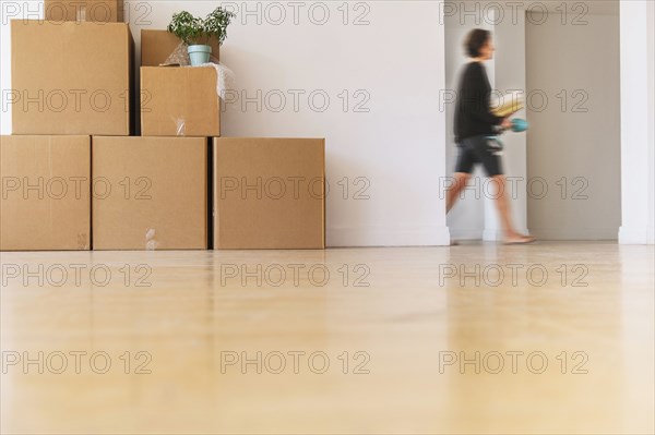 Woman walking near cardboard boxes stacked against wall