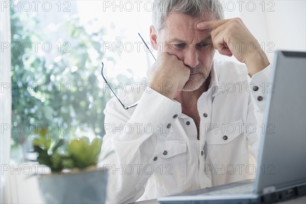 Frustrated older Caucasian man using laptop