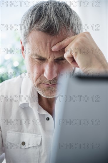 Frustrated older Caucasian man using laptop