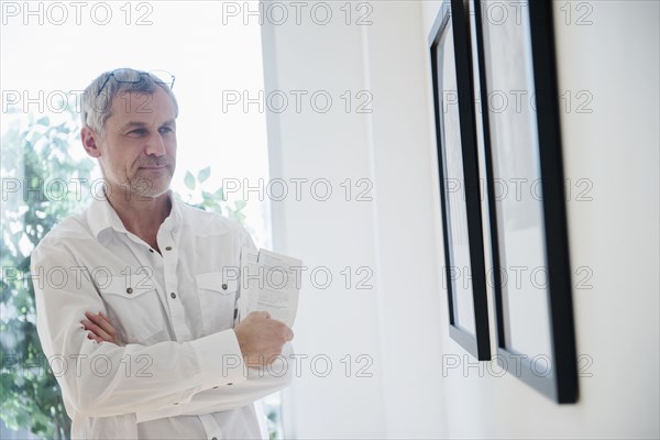 Older Caucasian man admiring artwork in gallery