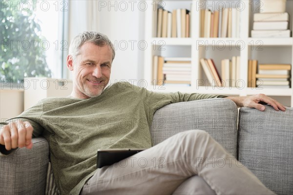 Older Caucasian man sitting on sofa with digital tablet