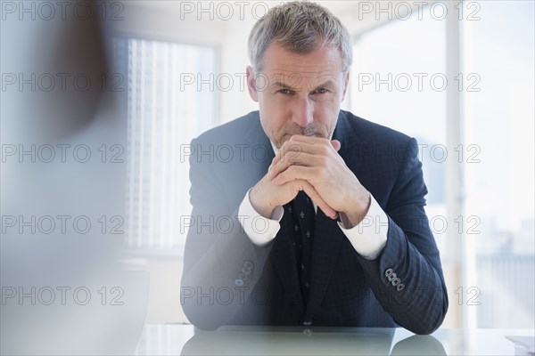 Serious older Caucasian businessman leaning on desk