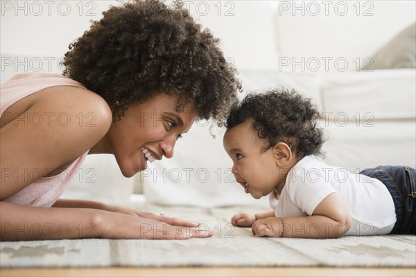 Mother playing face to face with baby son on floor