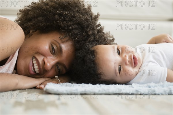 Mother and baby son laying head to head on floor
