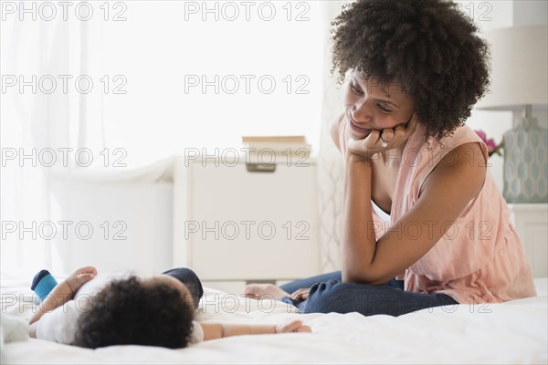 Mother watching baby son on bed