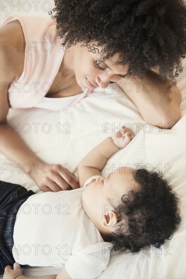 Mother watching baby son sleeping on bed