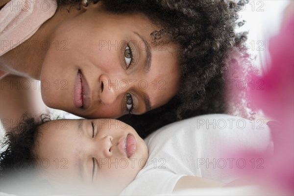 Mother cheek to cheek with baby son sleeping on bed