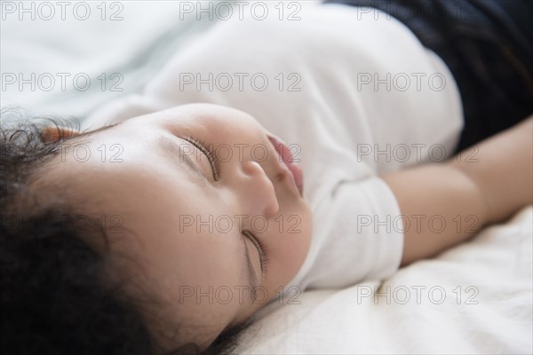 Mixed Race baby boy sleeping on bed