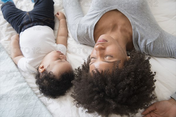 Mother and baby son sleeping on bed