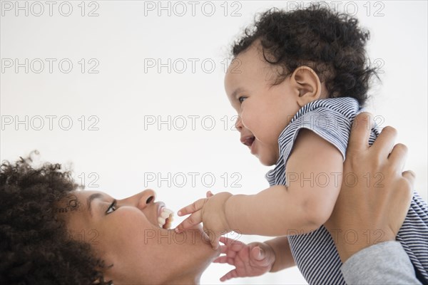 Mother lifting baby son face to face